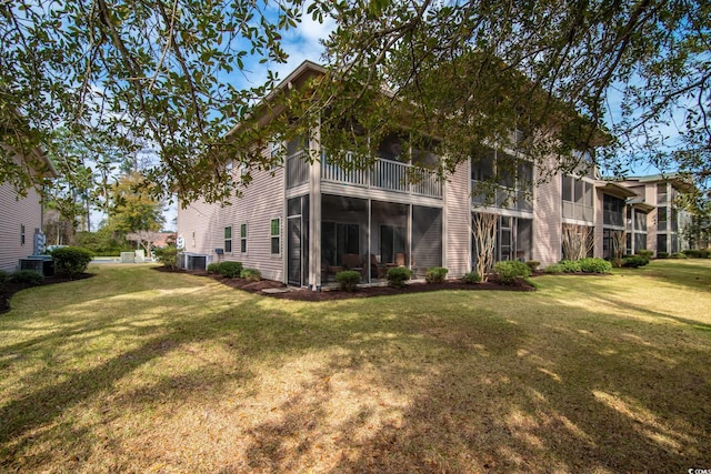 back of house with a balcony, central AC, a sunroom, and a lawn