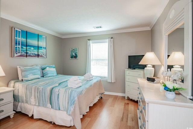 bedroom featuring baseboards, light wood-style floors, visible vents, and ornamental molding
