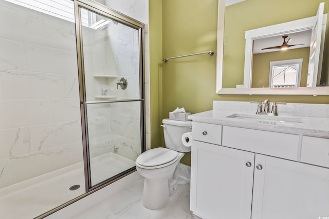 bathroom with vanity, toilet, ceiling fan, and a shower with shower door