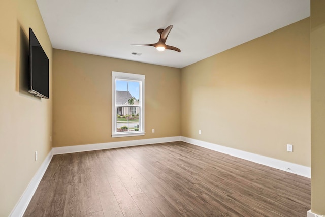 empty room with a ceiling fan, baseboards, visible vents, and wood finished floors