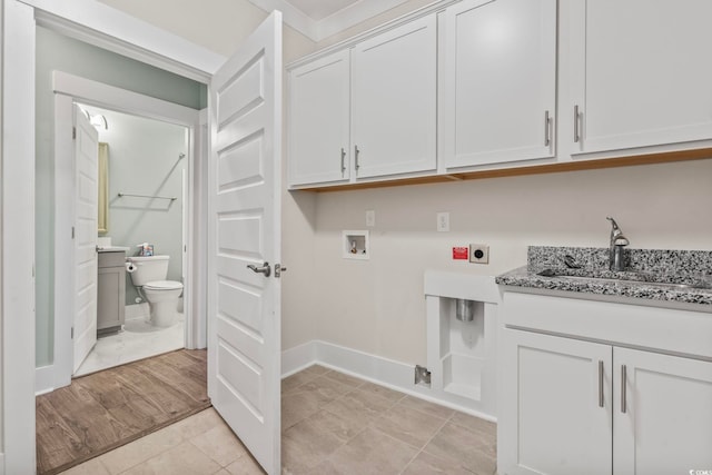 clothes washing area with washer hookup, hookup for an electric dryer, light hardwood / wood-style flooring, cabinets, and sink