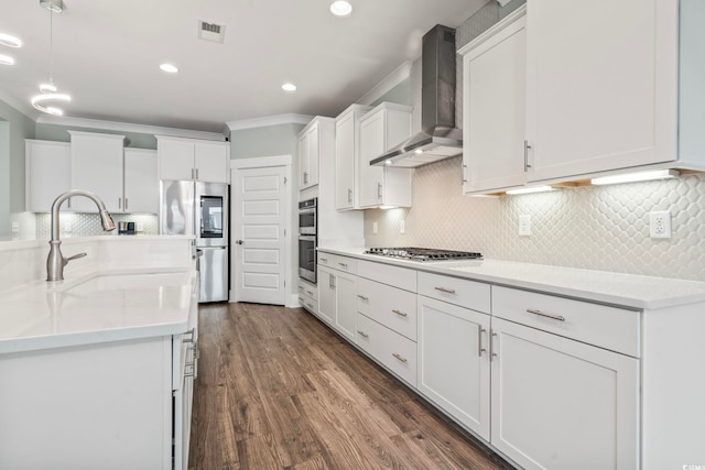 kitchen with appliances with stainless steel finishes, decorative backsplash, white cabinets, wall chimney exhaust hood, and dark hardwood / wood-style floors