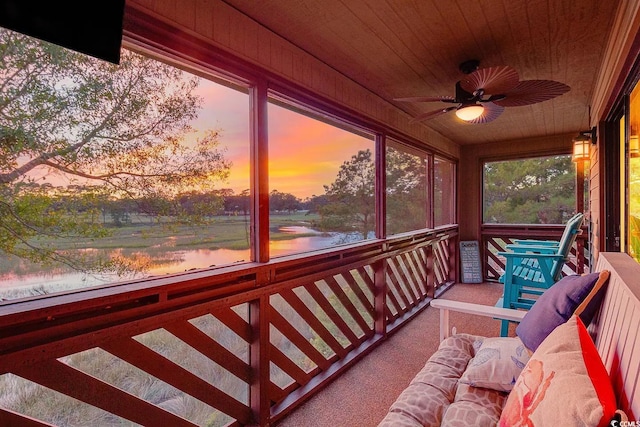 sunroom with wood ceiling, a water view, and ceiling fan