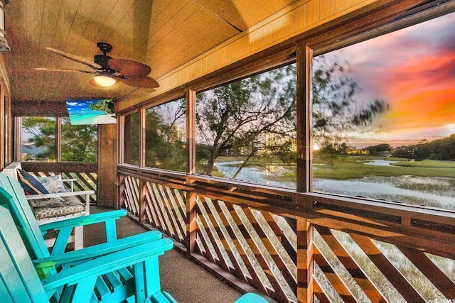 unfurnished sunroom with a water view and ceiling fan