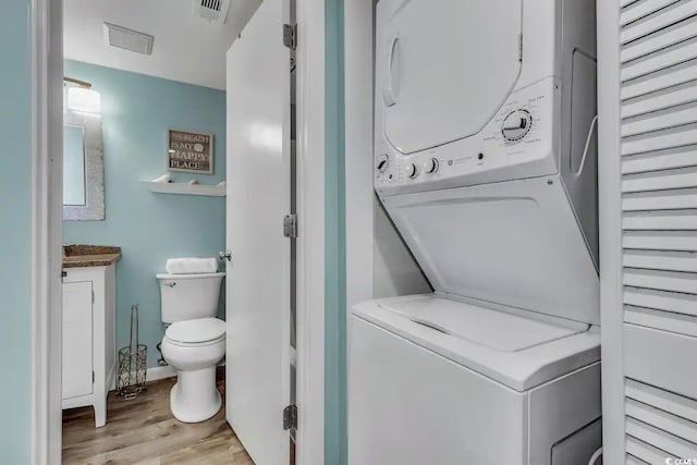 laundry area with light wood-type flooring and stacked washer and clothes dryer