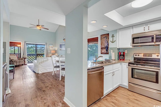 kitchen with sink, white cabinets, light hardwood / wood-style flooring, stainless steel appliances, and ceiling fan