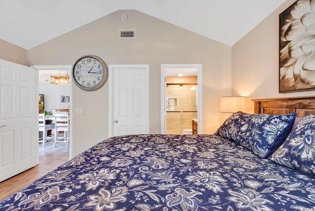 bedroom with vaulted ceiling, ensuite bathroom, and hardwood / wood-style flooring