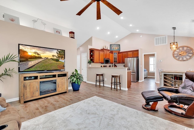 living room with light wood-type flooring, ceiling fan, and high vaulted ceiling