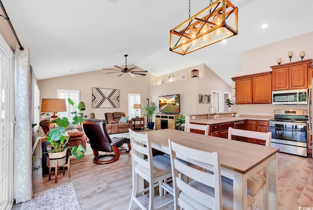 kitchen featuring appliances with stainless steel finishes, ceiling fan with notable chandelier, vaulted ceiling, and light wood-type flooring