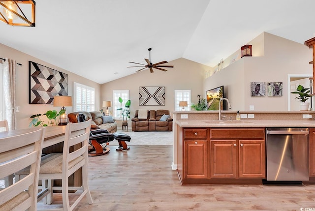 kitchen featuring ceiling fan, lofted ceiling, sink, stainless steel dishwasher, and light hardwood / wood-style flooring