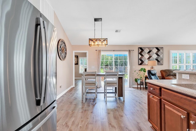 kitchen featuring pendant lighting, stainless steel fridge, light hardwood / wood-style floors, and plenty of natural light