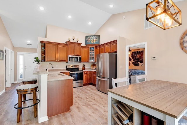 kitchen featuring hanging light fixtures, light hardwood / wood-style floors, kitchen peninsula, stainless steel appliances, and sink