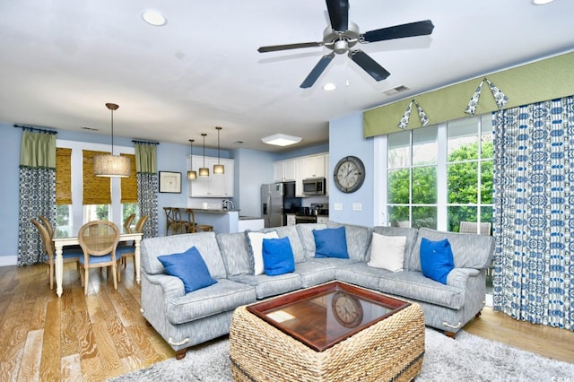 living room with light wood-type flooring and ceiling fan