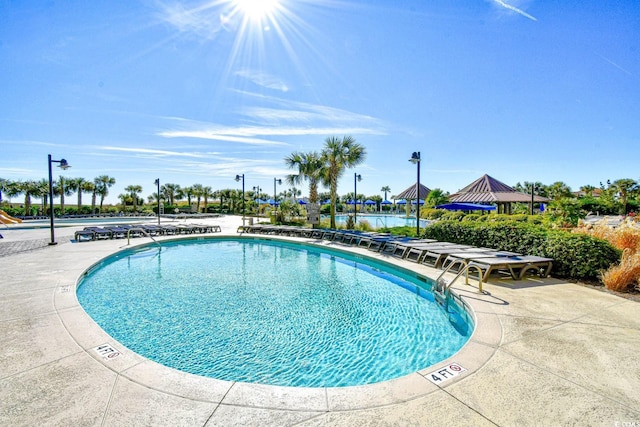 view of pool with a water view and a patio area