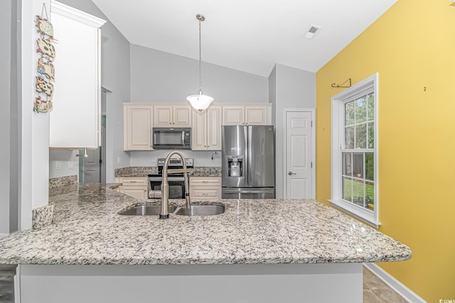 kitchen featuring light stone countertops, stainless steel appliances, kitchen peninsula, pendant lighting, and vaulted ceiling