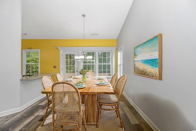 dining room featuring an inviting chandelier, sink, dark wood-type flooring, and vaulted ceiling