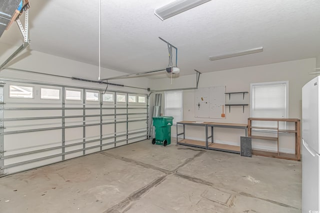 garage featuring white refrigerator and a garage door opener