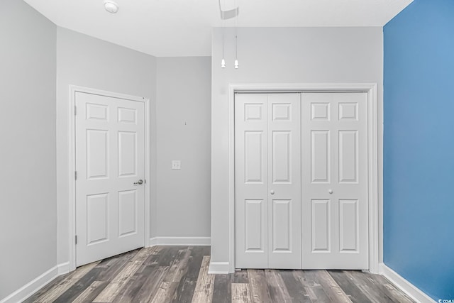 unfurnished bedroom featuring dark wood-type flooring and a closet