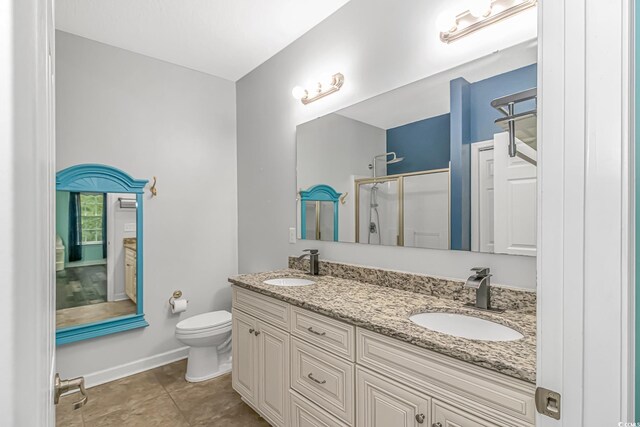 bathroom with toilet, vanity, tile patterned floors, and an enclosed shower