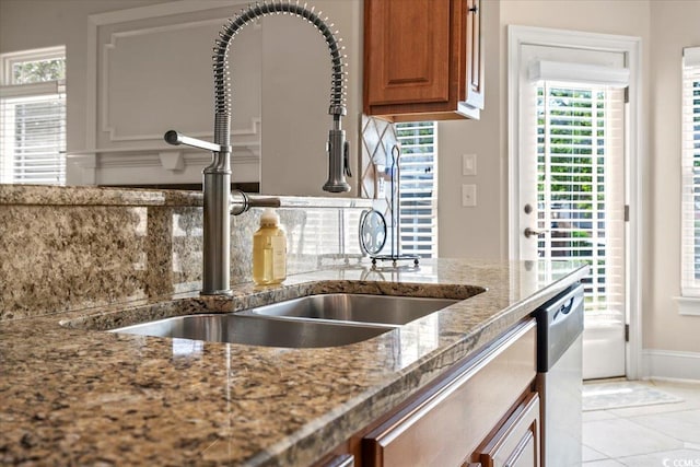 kitchen featuring light tile patterned floors, sink, tasteful backsplash, stainless steel dishwasher, and dark stone countertops