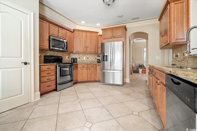 kitchen with light stone counters, light tile patterned flooring, ornamental molding, backsplash, and stainless steel appliances