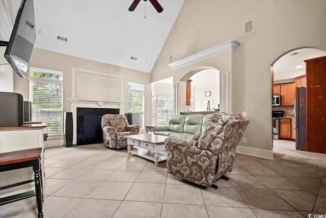 tiled living room with ceiling fan, crown molding, high vaulted ceiling, and a wealth of natural light