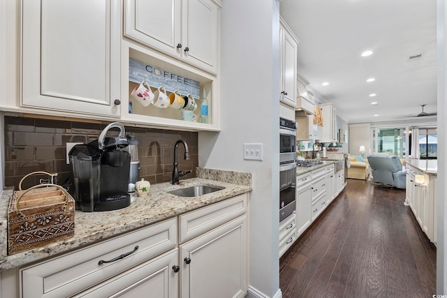 kitchen with ceiling fan, white cabinets, light stone counters, sink, and dark wood-type flooring