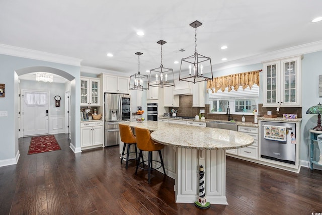 kitchen featuring pendant lighting, sink, a kitchen island, appliances with stainless steel finishes, and dark hardwood / wood-style flooring