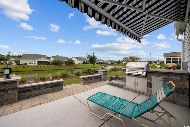 view of patio featuring a water view, an outdoor kitchen, and a grill