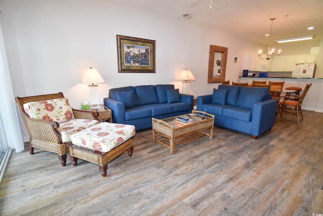 living room featuring a notable chandelier, a textured ceiling, and hardwood / wood-style floors