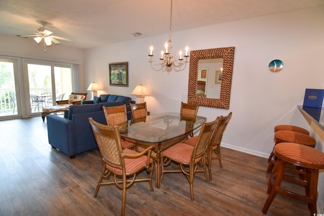 dining room with ceiling fan with notable chandelier and dark wood-type flooring