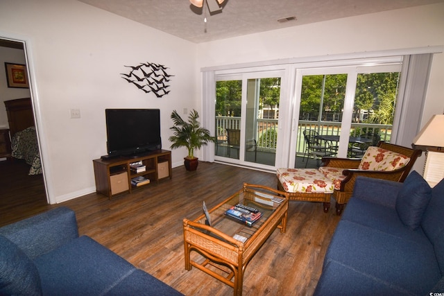 living room with ceiling fan, a textured ceiling, and dark hardwood / wood-style floors