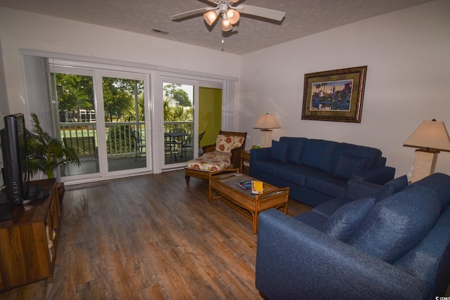 living room featuring wood-type flooring, ceiling fan, and a textured ceiling