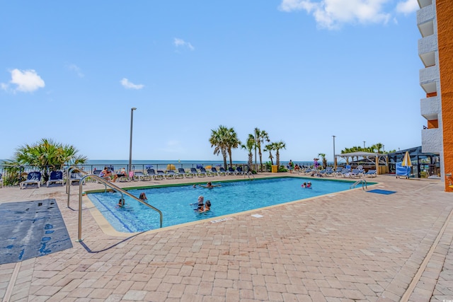 view of swimming pool featuring a patio and a water view