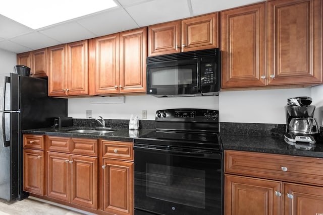 kitchen with dark stone countertops, a drop ceiling, sink, and black appliances