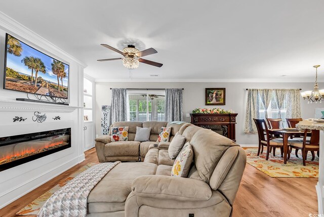 living room featuring light wood-type flooring, ceiling fan with notable chandelier, and ornamental molding