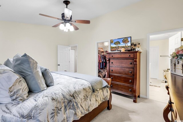 carpeted bedroom featuring a spacious closet, a closet, ensuite bathroom, and ceiling fan