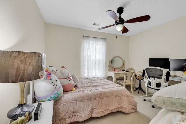 bedroom with ceiling fan, carpet floors, and a textured ceiling