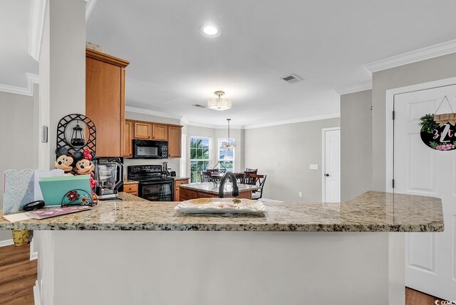 kitchen featuring black appliances, light hardwood / wood-style floors, ornamental molding, and decorative light fixtures