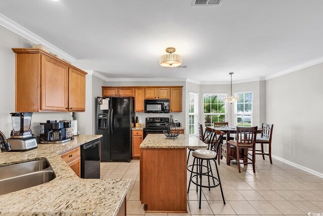 kitchen with light stone countertops, pendant lighting, black appliances, crown molding, and a chandelier