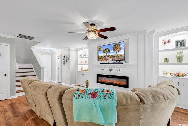 living room featuring wood-type flooring, ornamental molding, and ceiling fan