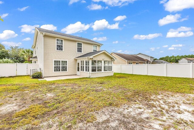 rear view of property featuring a patio, a yard, and a sunroom