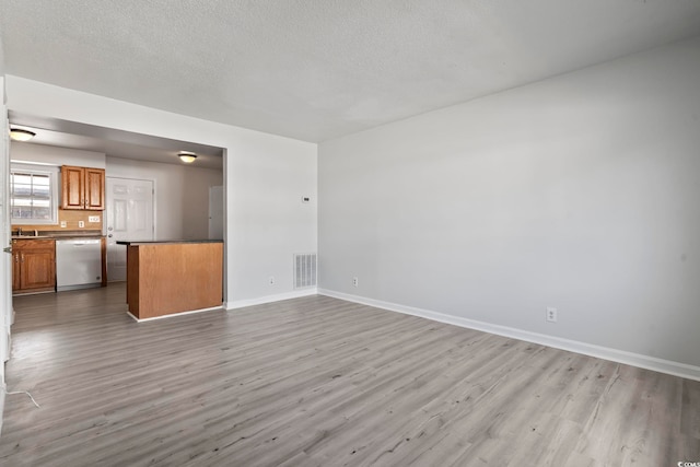 unfurnished living room featuring a textured ceiling, wood finished floors, and visible vents