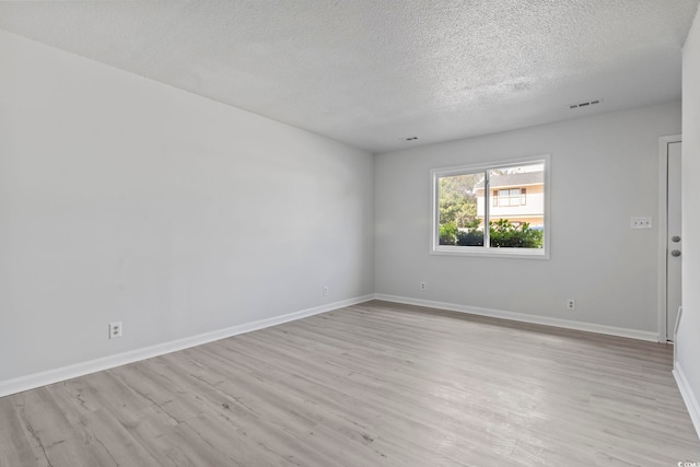 unfurnished room featuring a textured ceiling, light wood-style flooring, visible vents, and baseboards