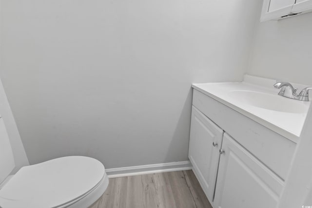 bathroom featuring toilet, vanity, baseboards, and wood finished floors