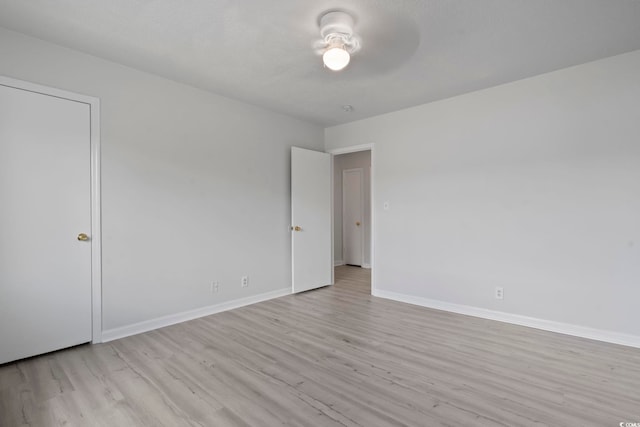 empty room with light wood finished floors, a ceiling fan, and baseboards