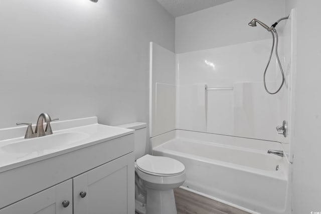 bathroom with a textured ceiling, toilet, wood finished floors, vanity, and shower / bathing tub combination