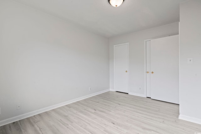 spare room with baseboards and light wood-style floors