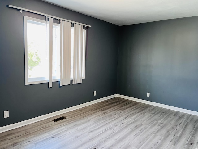 empty room with visible vents, baseboards, and wood finished floors