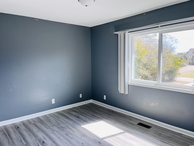 empty room with baseboards, visible vents, and wood finished floors